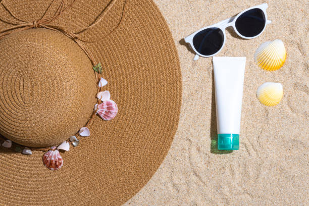 istock Sunscreen container mockup with straw hat, sea shells and sunglasses on sand background 1603751459
