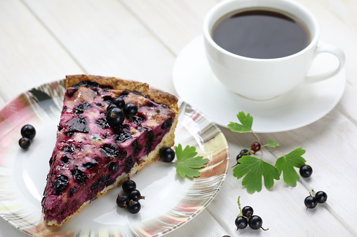 Sweet baked pie with summer season berries and cup of coffee on wooden background