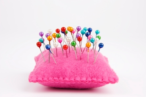 Handmade felt pin cushion with multicolored sewing pins stuck in