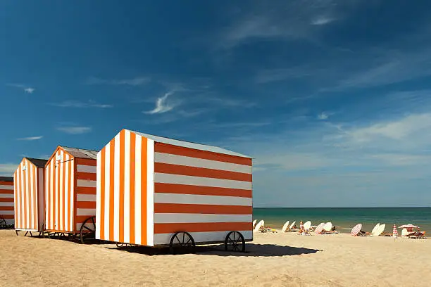 Red-white striped huts at a sunny beach.