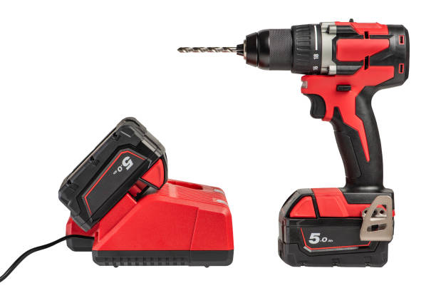 cordless drill with a drill on a white isolated background, side view. A set of a cordless drill and a charger that charges the battery from a screwdriver.