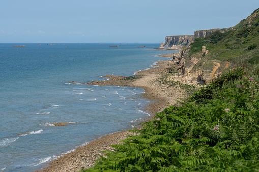 Battery of Longues-sur-Mer. View of the pebble beach surrounded by cliffs and marine vegetation