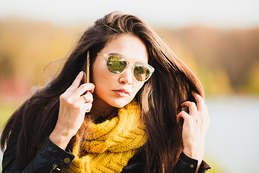 Pretty charming brunette with a bright appearance communicates on the phone with a serious look