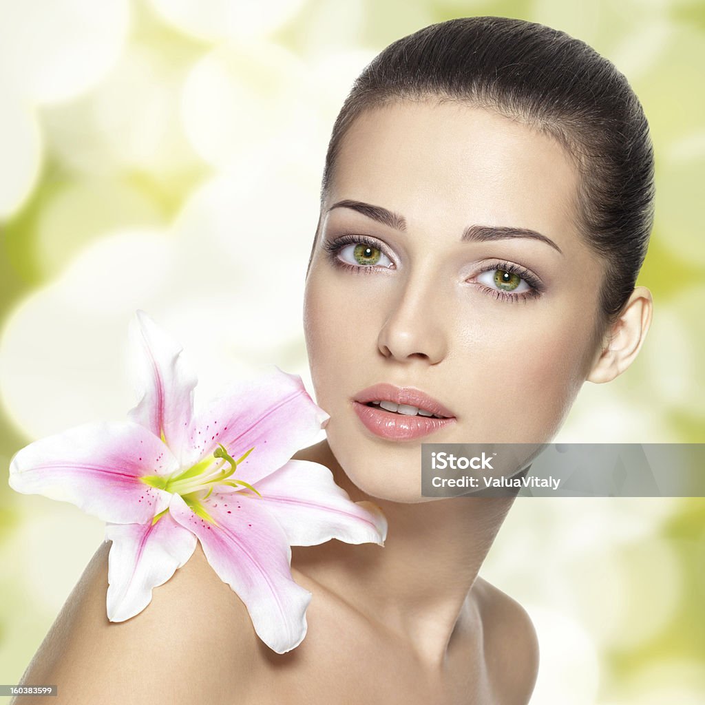 Beauty face of young woman with flower. Beauty face of young woman with flower. Beauty treatment concept. Blinking Background. Bokeh Adult Stock Photo