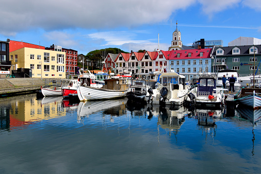 Tórshavn, Streymoy, Faroe Islands: sunny day in the Faroes capital, Tórshavn (Thor's harbour), locally called simply 'Havn' - colorful facades along Undir Bryggjubakka street  and boats in the old town harbor (Vestaravág, western harbor) - Cathedral bell tower in the background, Reyn- historic district.