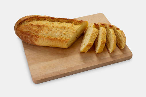 Sliced loaf of durum wheat semolina bread on wooden cutting board isolated on white with clipping path included