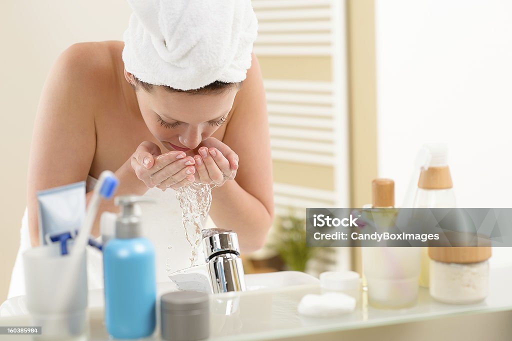 Mujer Lavando la cara anterior Lavamanos del baño - Foto de stock de 20 a 29 años libre de derechos