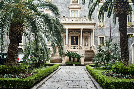 Courtyard with palm trees and the entrance to a historic townhouse in the city of Catania on the island of Sicily, Italy