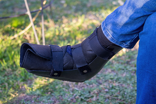 Foot of a person using an orthopedic plastic boot with Velcro closure for the treatment of ankle sprain