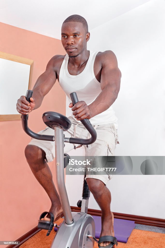 Hombre africano ejercicio en la bicicleta - Foto de stock de Ejercicio físico libre de derechos