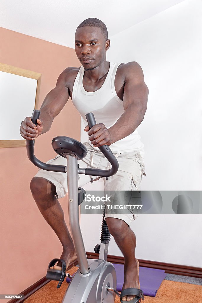 Uomo africano esercizio fisico sulla bicicletta - Foto stock royalty-free di Esercizio fisico