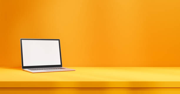 istock Laptop with white empty screen mock up on yellow table on orange wall backdrop 1603950231