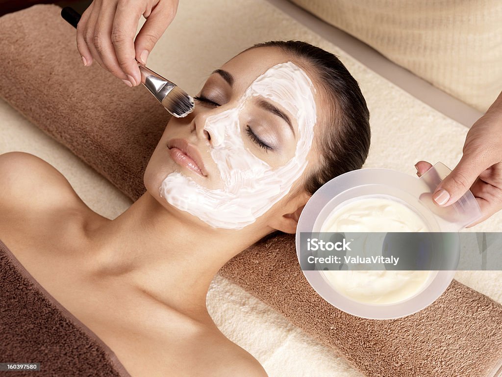 Spa therapy for woman receiving facial mask Spa therapy for young woman receiving facial mask at beauty salon - indoors Facial Mask - Beauty Product Stock Photo