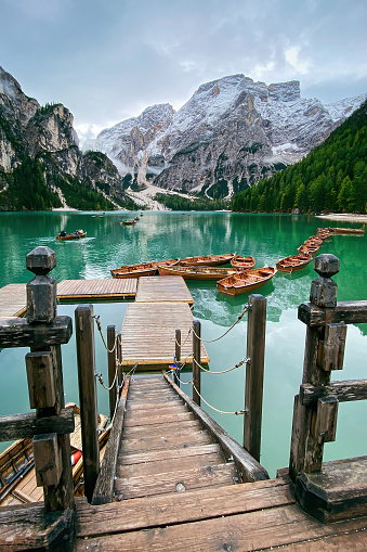 Scenic view of boats tethered on floating pier of Lake Braies (germ. Pragser Wildsee, ital. Lago di Braies) boathouse in Italy against cloudy sky
