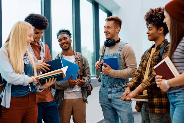 istock Multiracial group of happy college students talking in a hallway. 1604038671