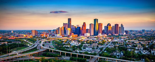 A view of major freeways converging near downtown Houston, Texas with the skyline beyond from an altitude of about 600 feet at sunset.