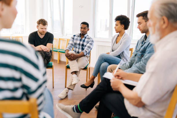 istock Back view to depressed black male drinker talking about alcohol addiction abuse sitting in circle speak to diverse addicted people at group therapy session. 1604174846