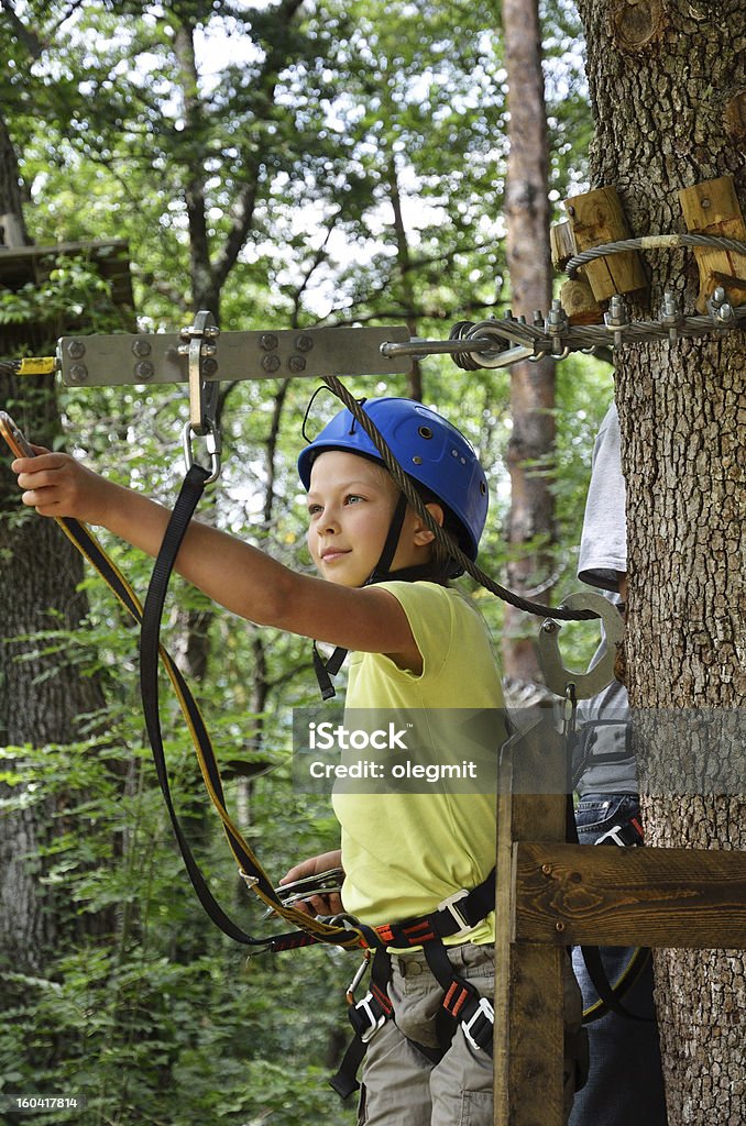Preteen girl at the rope course Teenage girl is standing on the platform high up on the tree. She is photographed at the rope parkour outdoors. Child Stock Photo