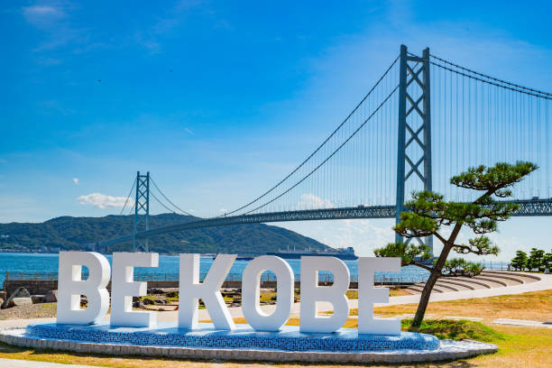 ein foto der japanischen akashi-kaikyō-brücke und des "be kobe"-denkmals. - kobe bridge japan suspension bridge stock-fotos und bilder