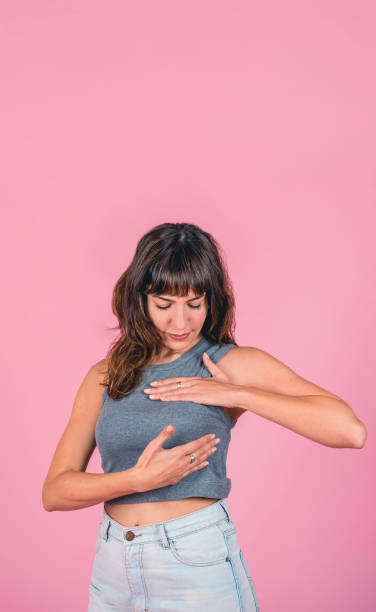 Woman doing a Breast Self-Exam checking up breast changes over pink background. Copy space Woman doing a Breast Self-Exam checking up breast changes over pink background. Copy space self test stock pictures, royalty-free photos & images