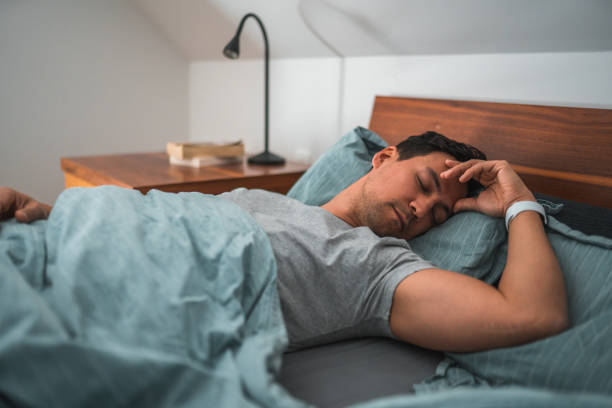 istock Mid Adult Man Sleeping in Bed Wearing a Watch 1604195028