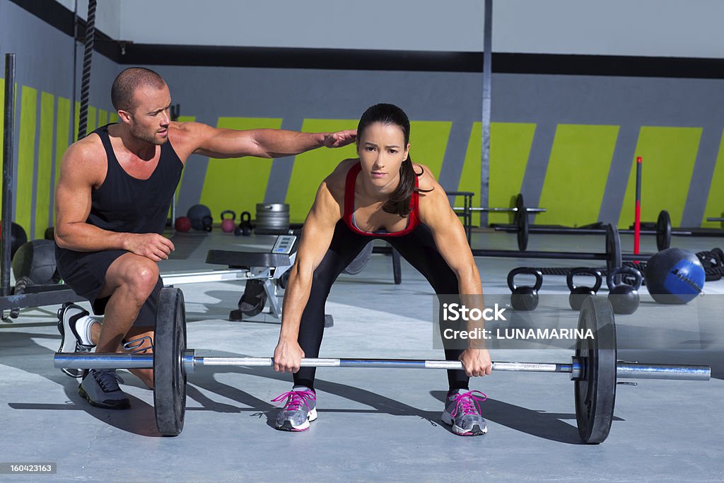 Personal trainer with woman performing deadlift gym personal trainer man with weight lifting bar woman workout in gym exercise 20-29 Years Stock Photo