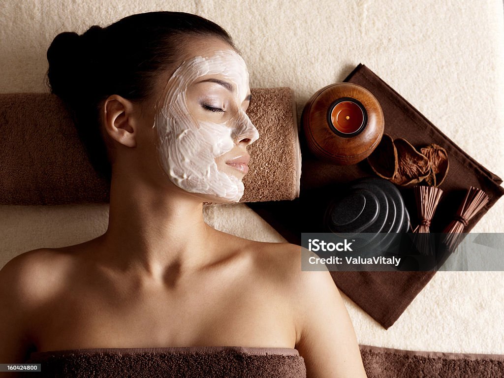 Woman relaxing with a facial mask at a beauty spa Young woman relaxing with facial mask on face at beauty salon- indoors Facial Mask - Beauty Product Stock Photo