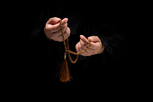 The image of a Muslim woman's hand, Islamic prayer, and her hand holding a rosary beads or tasbih.