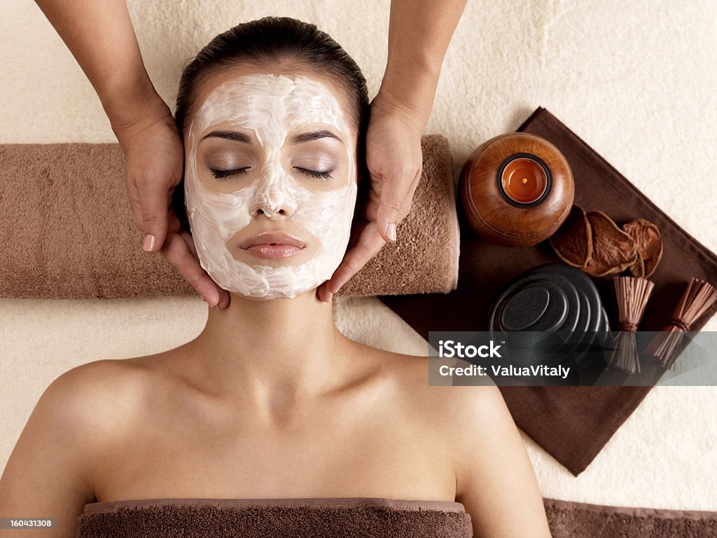 Spa massage for woman with facial mask on face Spa massage for young woman with facial mask on face - indoors Adult Stock Photo