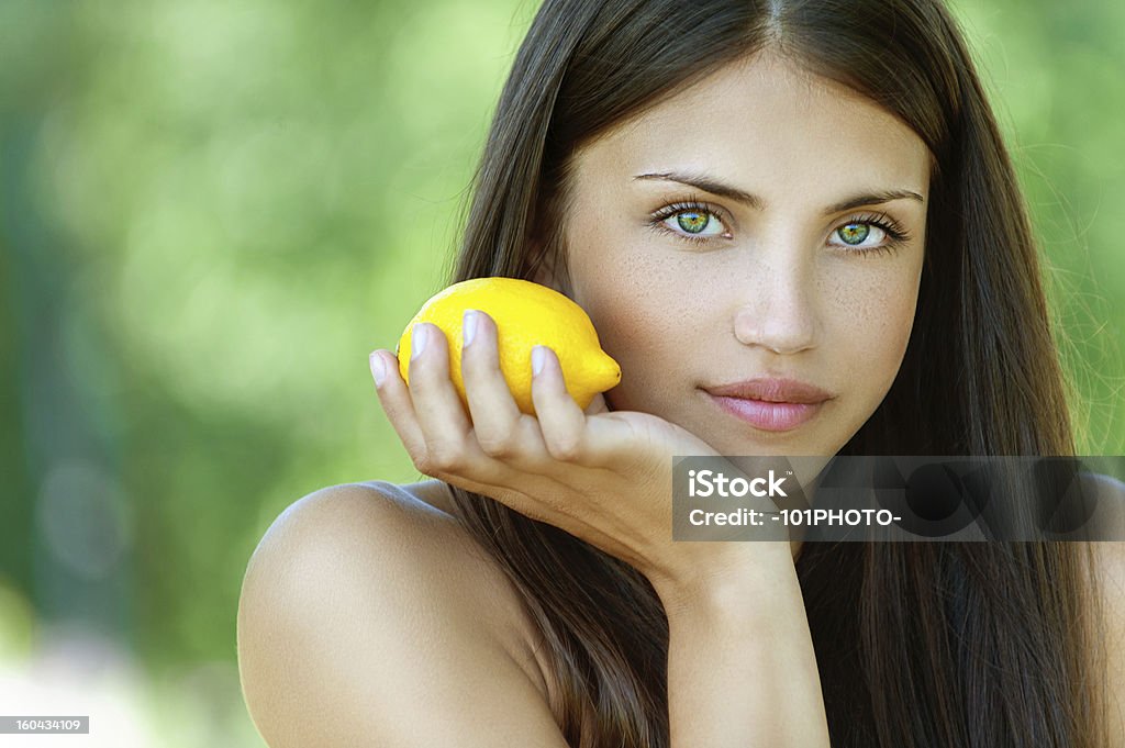 young woman with yellow lemon Portrait of beautiful young woman with yellow lemon, against background of summer green park. Adult Stock Photo