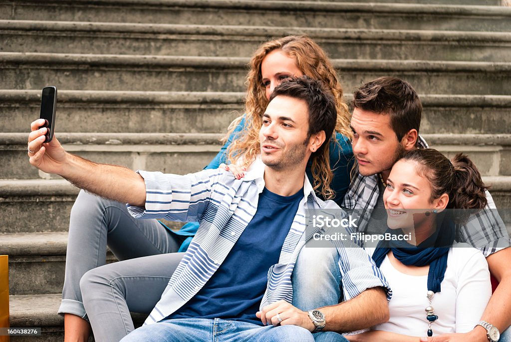 Czterech przyjaciół siedząc na schody biorąc zdjęcie z telefonu - Zbiór zdjęć royalty-free (16-17 lat)