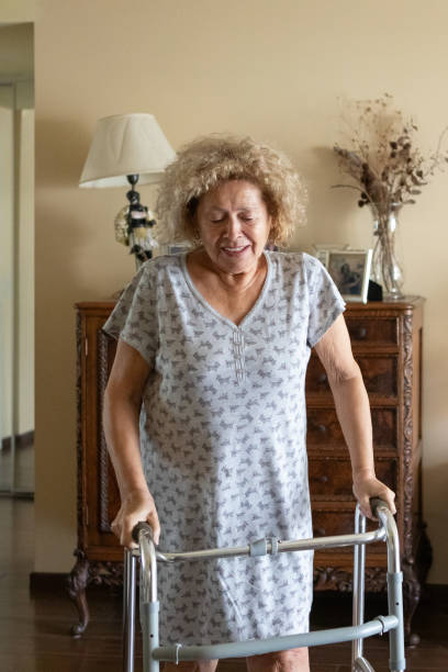 istock Elderly woman with a disability and a walker exercising 1604390304