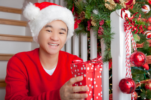 Happy asian man sitting on staircase with gift