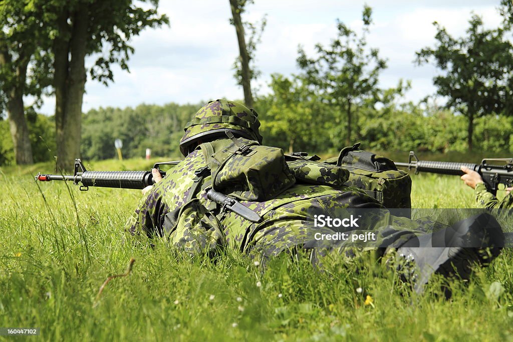 Lying soldiers on Patrol Lying soldiers in Danish camouflage uniform with M16 rifle on Patrol Denmark Stock Photo