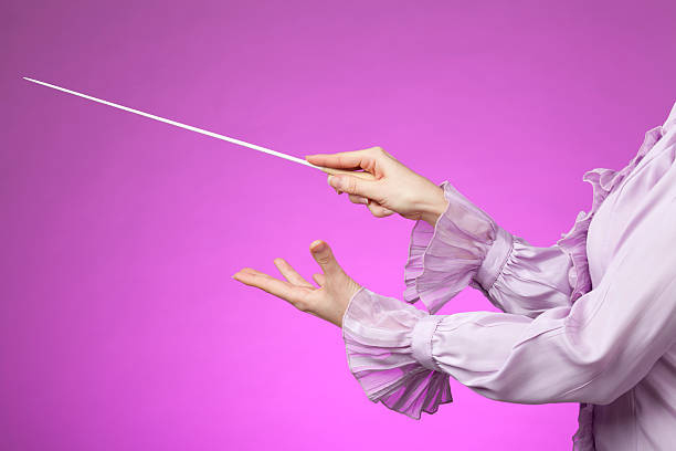 Orchestra conductor Female orchestra conductor hands, one with baton. Pink background. conductors baton photos stock pictures, royalty-free photos & images