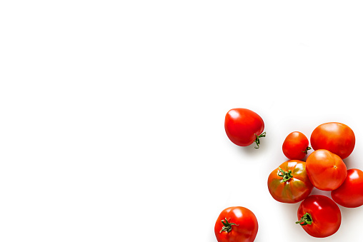 Closeup of fresh juicy organic tomatoes from the garden in a craft bag on isolated white background from above