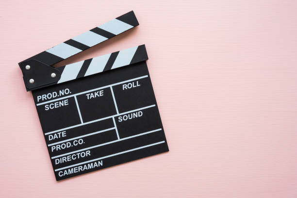 istock Cinema clapperboard on pink wooden background. 1604489743