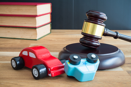 Car accident,  auto insurance and judge gavel law concept. Car model crash, wooden judge hammer and law textbook on wooden table background.