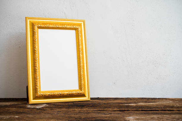 Blank golden vintage styles photo frame on table with white wall background. Art, decoration, creative design concept.