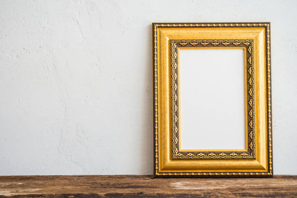 istock Blank golden vintage styles photo frame on table with white wall background. 1604552240