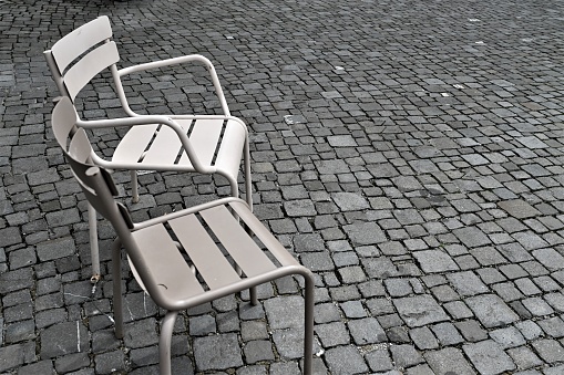 The two wooden chairs placed on a brick walkway in an outdoor setting