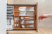 Woman opening kitchen drawer with wooden cutlery tray