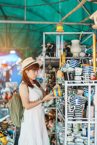Young asian woman traveler holding Mug in Ceramics souvenir shop for tourists, Girl visit at Lampang, Thailand