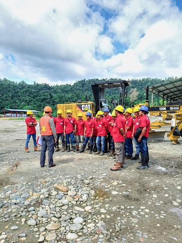 Nabire, Papua, Indonesia - 07-17-2019: People are assembling in a wide field to join an Occupational Health and Safety training. A trainer gives instructions to participants.