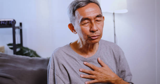 istock Asian old man having difficulty breathing while sitting on the sofa at home. 1604636810