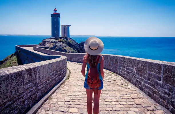 Rear view of woman tourist looking at view of lighthouse in Brittany-france