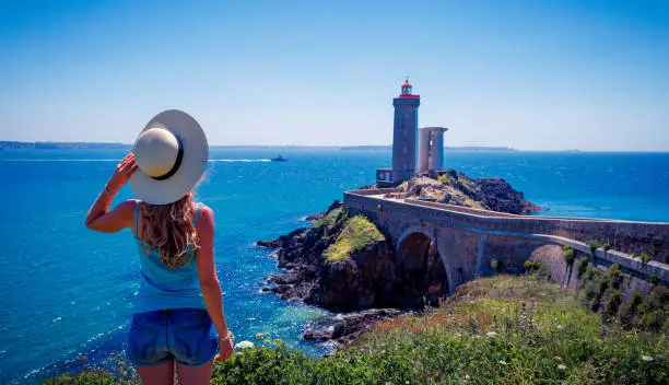 Rear view of holiday maker looking at view of lighthouse in Brittany-france