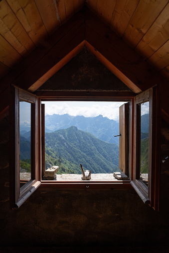 The view the green mountains from the window in a small hut, bivacco, in the Italian Alps.