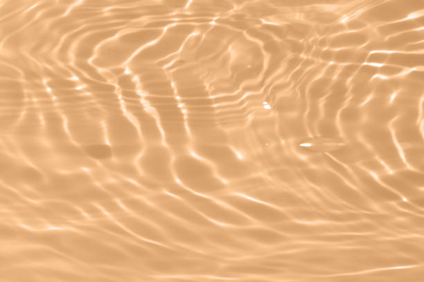 istock Cream water with ripples on the surface. Defocus blurred transparent pink colored clear calm water surface texture with splashes and bubbles. Water waves with shining pattern texture background. 1604682446