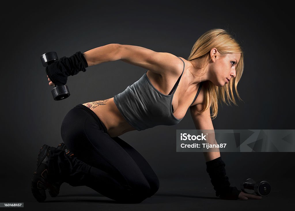 Fit woman exercising with weights over a dark background Abdomen Stock Photo